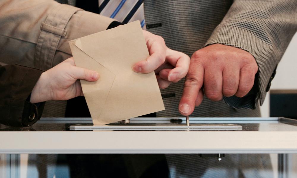 voter box with ballot being inserted