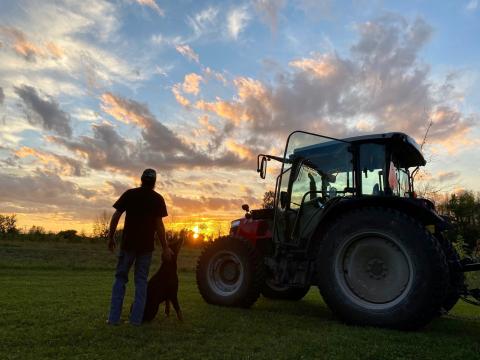 A local farmer stands in his field at sunset. 