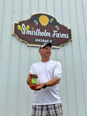 Glenn Smirle holds up a jar of his locally produced honey. 
