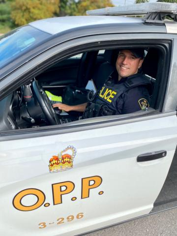 Tylor Copeland sits in his police cruiser on a sunny day. 