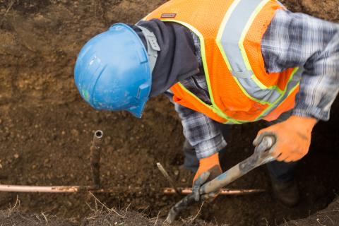 A man fixing pipes in the ground.