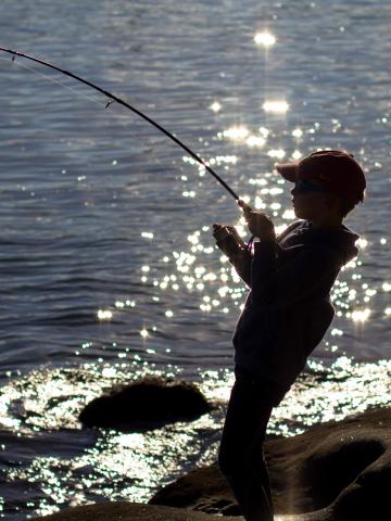 Kid fishing with road on lakes edge