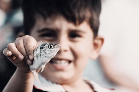 Child holding small silver fish